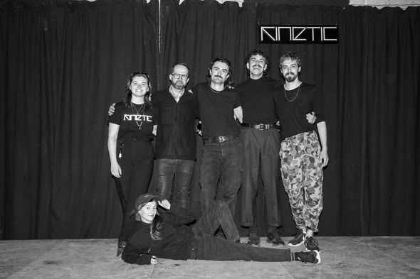 People in KINETIC T-shirts on stage under the KINETIC neon
