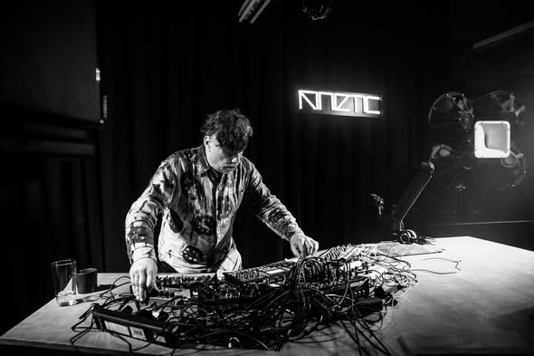Patching cables during the Gas of Latvia live set, KINETIC neon behind