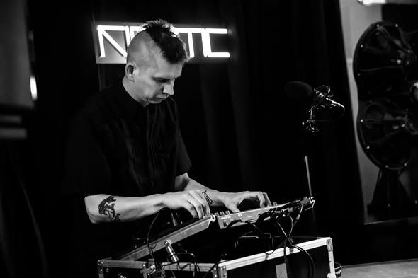 A performer playing under the KINETIC neon