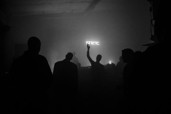 Crowd silhouettes in front of the KINETIC neon at 1983