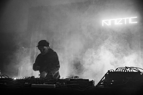 A DJ in stage haze under the KINETIC neon